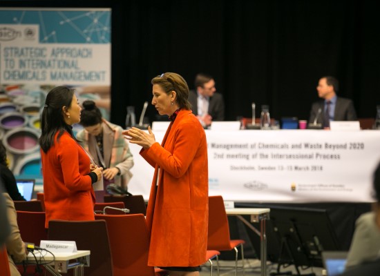 Two women in orange coats in dialogue on the SAICM conference.