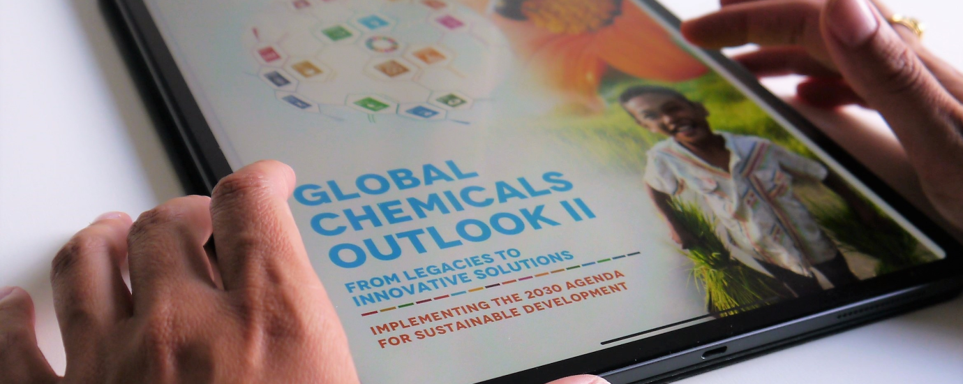 A tablet showing the coverpage of the Global Chemicals Outlook Two Document held between two hands