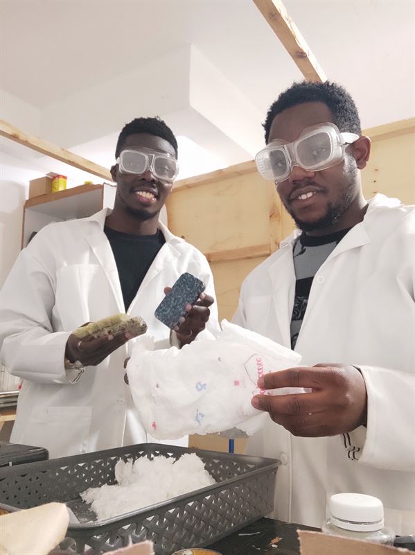 two black men holding a diaper and some pellets.