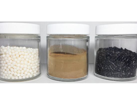 container with lignin (brown powder) and co-polymers (white pellets) in their proprietary process to produce the biopolymer (black pellets).