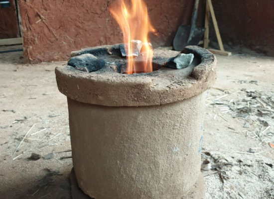 cylinder shaped stove made out of clay, a fire burning inside the opening