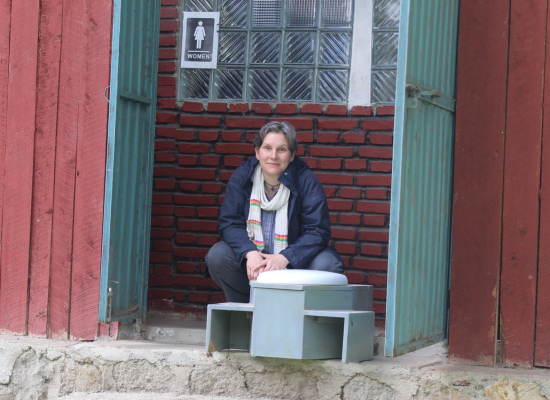 Woman squatting in front of EcoSanitation toilet house