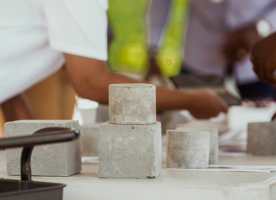 Grey, rectangular and cylindric blocks of cement like material on a table, close shot