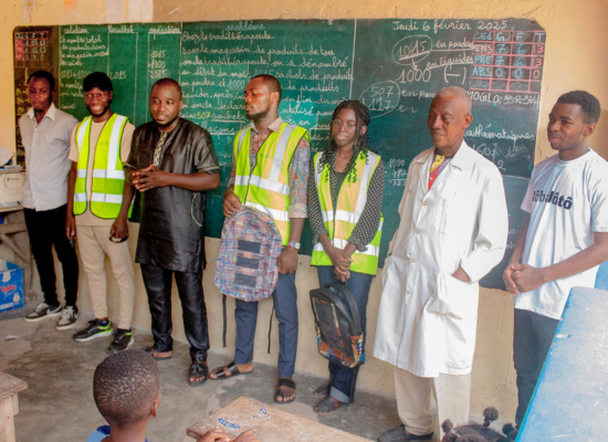 7 african people (6 men, 1 woman) standinginfront of a class before a green chalkboard.